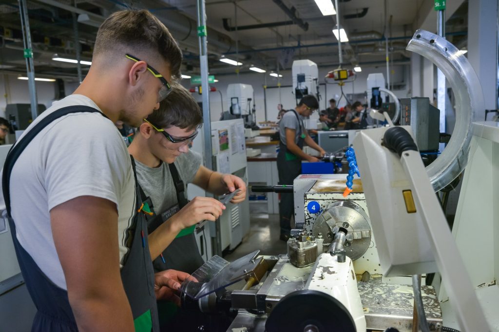 studenti care lucreaza la un utilaj